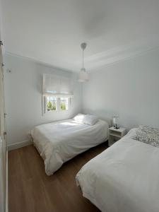 2 camas en una habitación blanca con ventana en Villa Mariaje, en Cazalla de la Sierra