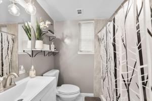 a white bathroom with a toilet and a sink at Elegant 1-BR Apartment in Silver Spring
