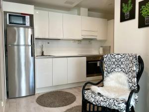 a kitchen with a refrigerator and a chair in it at Kotimaailma Apartments Lahti in Lahti