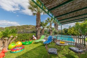 a backyard with chairs and tables and palm trees at Iliachtida House in Sounio