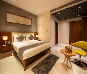 een slaapkamer met een groot bed en een gele stoel bij Morvee Hotels Durgapur in Durgapur