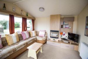 uma sala de estar com um sofá e uma televisão em 6 Berth Caravan With Free Wifi For Hire In Suffolk Ref 68073bs em Lowestoft