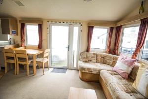 uma sala de estar com um sofá e uma mesa em 6 Berth Caravan With Free Wifi For Hire In Suffolk Ref 68073bs em Lowestoft