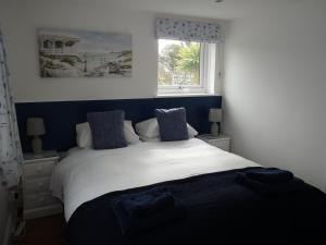 a bedroom with a white bed and a window at Gwyndaf Holiday Cottage in Llangoed