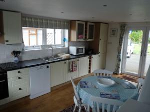 uma cozinha com uma mesa, um lavatório, uma mesa e cadeiras em Gwyndaf Holiday Cottage em Llangoed