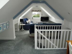 a attic room with a bed and a couch at Gwyndaf Holiday Cottage in Llangoed