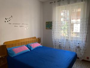 Un dormitorio con una cama azul con almohadas rosas y azules en Tra mare e arte en Lido di Ostia