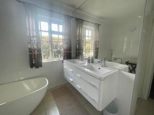 ein weißes Badezimmer mit Waschbecken, Badewanne und Toilette in der Unterkunft Lakeview Cottage: Rural Retreat in Pampoenkraal + 28 Fotos