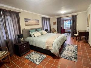 ein Schlafzimmer mit einem Bett und ein Wohnzimmer mit einem Schreibtisch in der Unterkunft Lakeview Cottage: Rural Retreat in Pampoenkraal