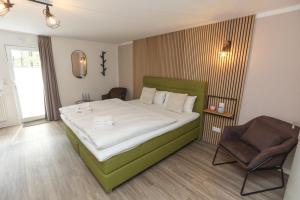 a bedroom with a large bed and a chair at Falk & Frei Selketal Resort in Meisdorf