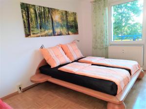 ein Schlafzimmer mit einem Bett mit orangefarbenen Kissen und einem Fenster in der Unterkunft Helles Apartment mit Balkon am Großen Garten nahe Stadtzentrum in Dresden