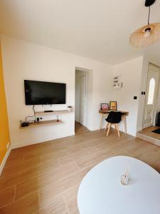 sala de estar con mesa y TV en la pared en Happy House, en Torcenay