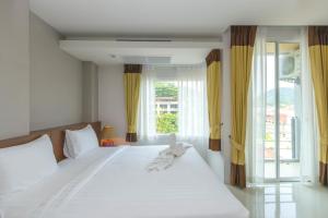 a bedroom with a large white bed with a window at Baan Lukkan Patong Resort in Patong Beach