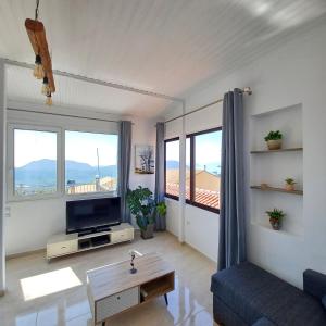 a living room with a couch and a tv and windows at Venetis Home in Áyios Pétros