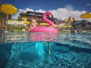 a person in a pink flamingo in a swimming pool at Hotel Saalbacher Hof in Saalbach Hinterglemm