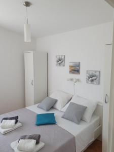 a white bedroom with a bed with two towels on it at Apartmani Kunteja in Pag