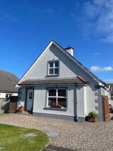 a white house with a window in a driveway at Wind Rose Rooms in Ballycastle