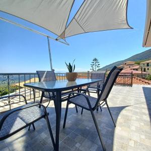 a table and chairs on a balcony with an umbrella at Venetis Home in Áyios Pétros