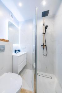 a white bathroom with a shower and a toilet at The World is Yours seaside apartment in Liepāja