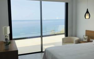 a bedroom with a bed and a large glass window at Villa El Buzo in Zahara de los Atunes