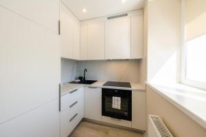 a kitchen with white cabinets and a window at The World is Yours seaside apartment in Liepāja