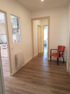 salon z czerwonym krzesłem i kuchnią w obiekcie Agréable appartement lumineux au centre-ville w mieście Oyonnax