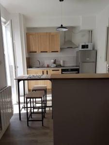 una cocina con encimera y algunas sillas. en Agréable appartement lumineux au centre-ville, en Oyonnax
