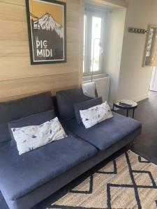 un sofá azul con 2 almohadas en la sala de estar en Ginkobiloba : Appartement cosy en cœur de ville, en Bagnères-de-Bigorre