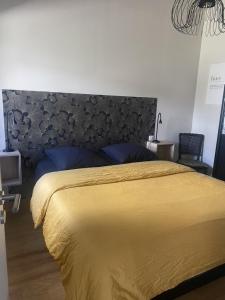 1 dormitorio con 1 cama grande con colcha amarilla en Ginkobiloba : Appartement cosy en cœur de ville, en Bagnères-de-Bigorre