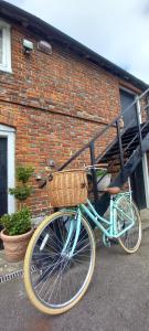 a blue bike with a basket parked in front of a brick building at Plumpton Barn in Ashford
