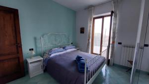 a bedroom with a bed with a blue headboard and a window at La Casetta nel Bosco in Ischia