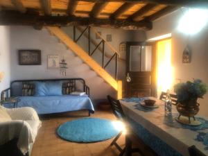 a living room with a blue bed and a table at Casal dos Carpinteiros - Carpenters Couple in Silveira