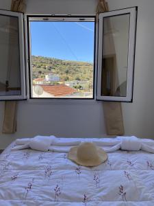 1 cama con sombrero en una habitación con 2 ventanas en Orphanos House en Kamilari