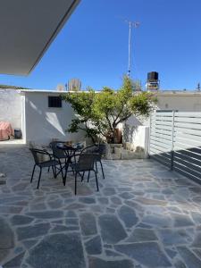 een patio met een tafel en stoelen en een boom bij Orphanos House in Kamilari