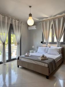 a bedroom with a bed with white pillows and curtains at Villa Rose Ground Floor - Private Swimming Pool Garden in Koskinou