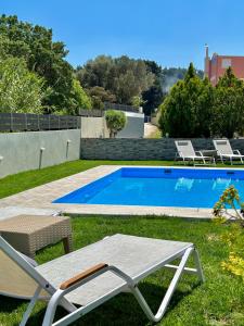 a swimming pool with two lawn chairs and a table at Villa Rose Ground Floor - Private Swimming Pool Garden in Koskinou