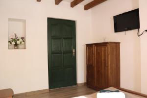 a room with a green door and a tv on a wall at Zöld Tanya Vendégház és Rendezvényközpont in Kiskunmajsa