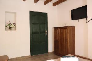 Habitación con puerta verde y TV en la pared. en Zöld Tanya Vendégház és Rendezvényközpont, en Kiskunmajsa