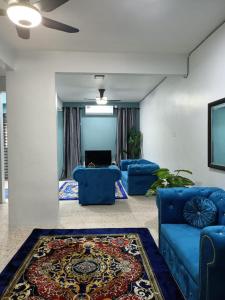 a living room with blue couches and a rug at RIANI HOMESTAY in Kertih