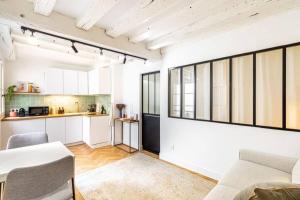 a kitchen and living room with white walls and windows at GuestReady - Wabi-Sabi Minimal in Marais in Paris