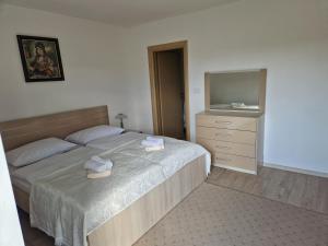 een slaapkamer met een bed en een dressoir met handdoeken erop bij Apartman Potok in Livno