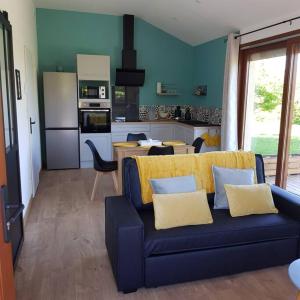 a living room with a blue couch and a kitchen at studio avec terrasse au calme in Jayat
