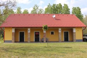 a small yellow house with a red roof at Zöld Tanya Vendégház és Rendezvényközpont in Kiskunmajsa