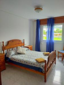 a bedroom with a bed and a window with blue curtains at Piso 4 habitaciones Valdoviño cerca de la Playa in Valdoviño