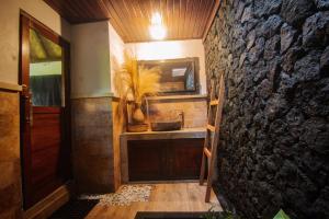 a bathroom with a sink and a stone wall at Bintang House in Kintamani