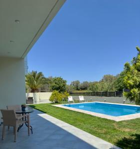 a patio with a pool and a table and chairs at Villa Rose Ground Floor - Private Swimming Pool Garden in Koskinou