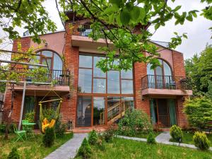 uma casa de tijolos com janelas grandes em Hestia - Hotel, Wine and View em Telavi