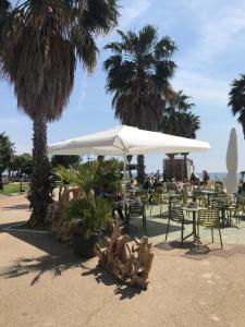 einen Tisch und Stühle mit einem weißen Regenschirm und Palmen in der Unterkunft Happy Home in Savona