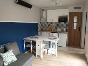 Una cocina y una sala de estar con una mesa y sillas blancas. en Kwiat Jabłonki, en Wikno
