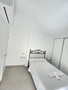 biała sypialnia z 2 łóżkami i ręcznikami w obiekcie Apartamento Centro Ronda 2 w mieście Ronda